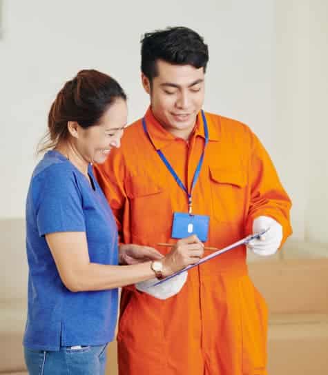 A man in orange coveralls and a woman signing documents.